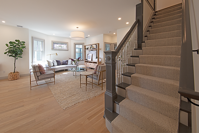 Living room opening to a custom stair hall with painted millwork and a wood handrail
